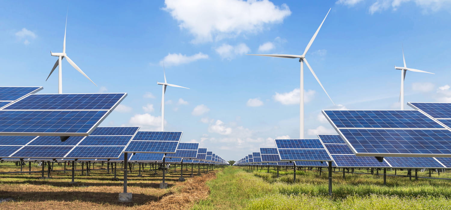 Low shot of solar panels with wind turbines in the background